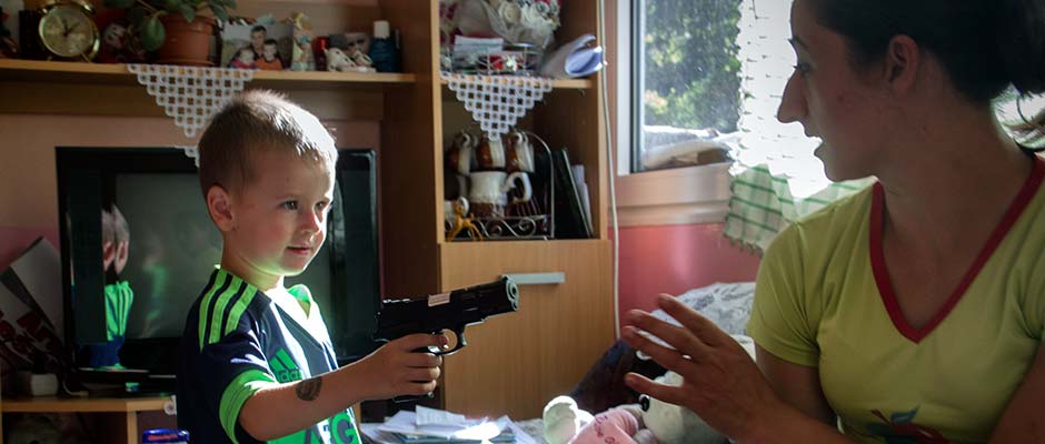 Arman Buljic, at play, points a gun at his mother Admira. | Arman Buljić se igra držeći pištolj uperen u majku Admiru